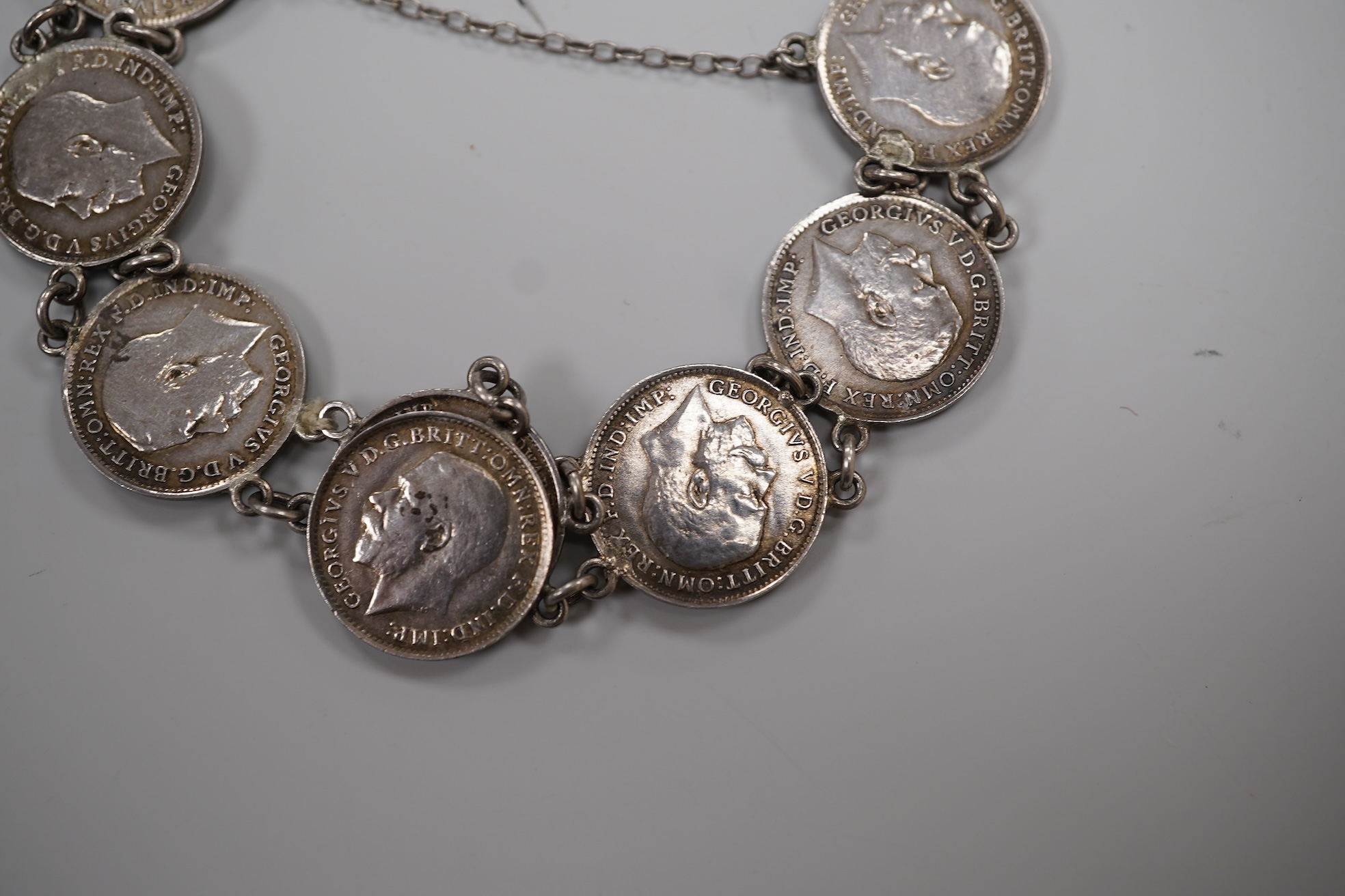 A cased early 20th century 9ct and single stone split pearl set bar brooch, 42mm and a white metal coin bracelet.